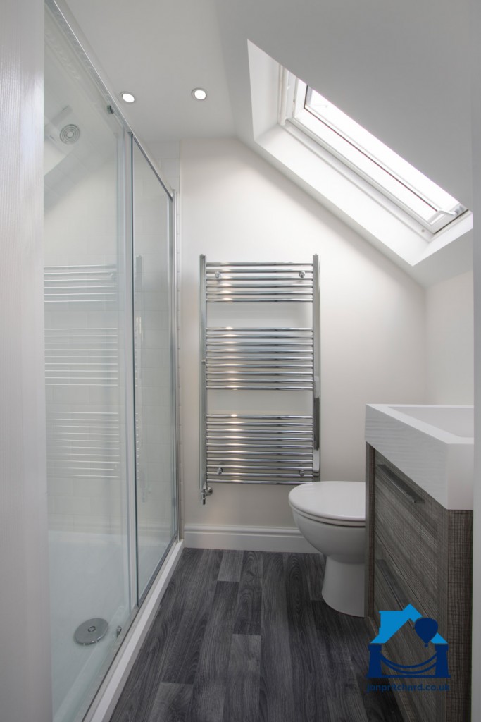 Portrait orientation image of a chic loft conversion ensuite shower room, with VELUX window.