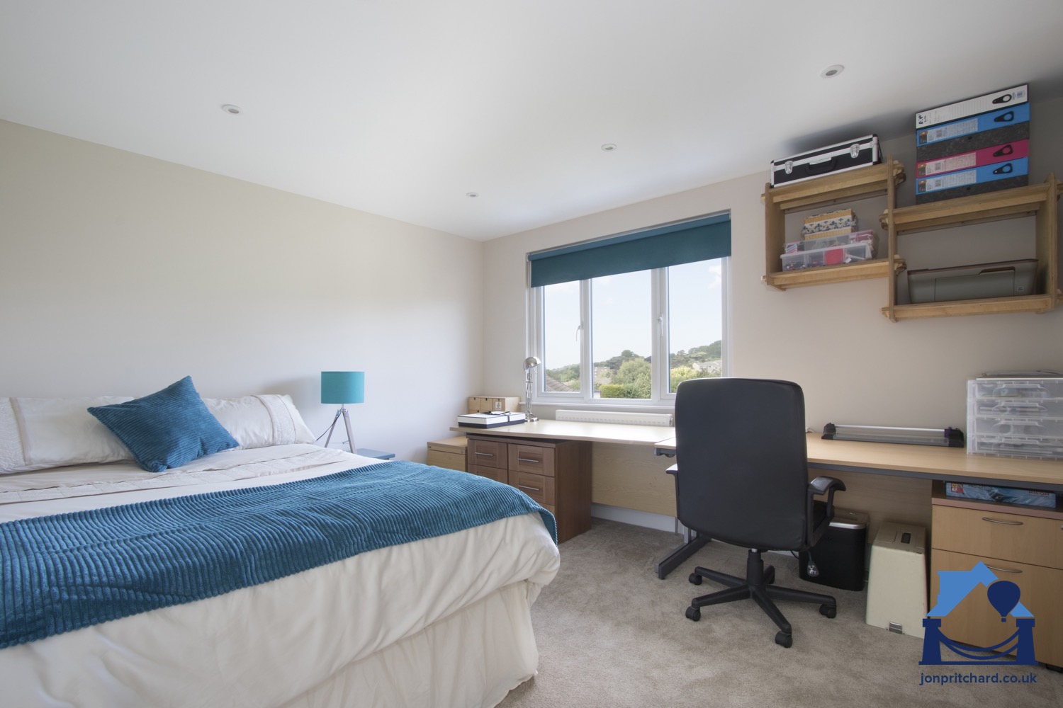 Loft bedroom with long desk and office furniture along the wall with window