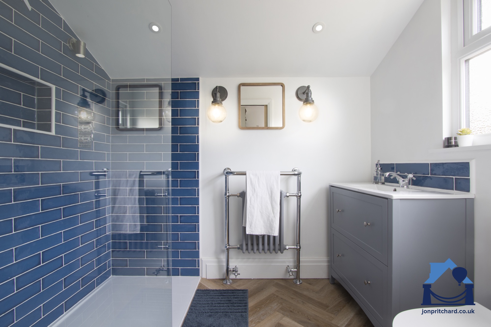 Chic, tidy loft conversion bathroom by Jon Pritchard, Bristol, UK featuring double-width walk-in shower, classic navy blue brick tiling and white walls with a parquet floor.