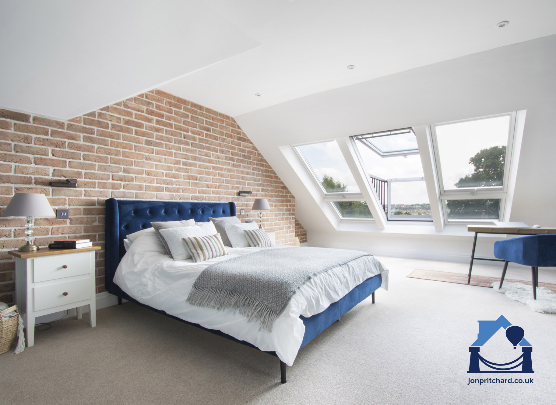 Wide loft conversion bedroom with exposed brick feature wall and large VELUX roof window balcony with view