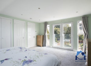 double bedroom in a Bristol loft conversion showing view across the bed to double doors with a garden view